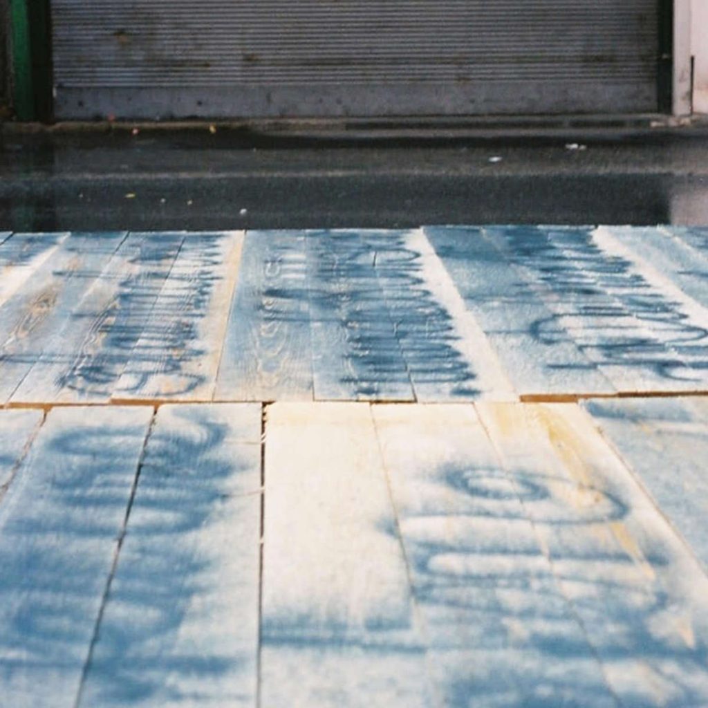 Am Boden liegende Bretter, die mit blauer Farbe besrpüht sind.